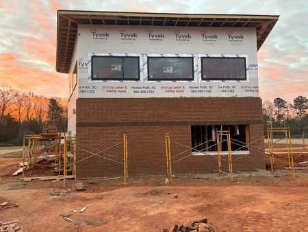 Construction site: Two-story building with brick facade and Tyvek wrap.