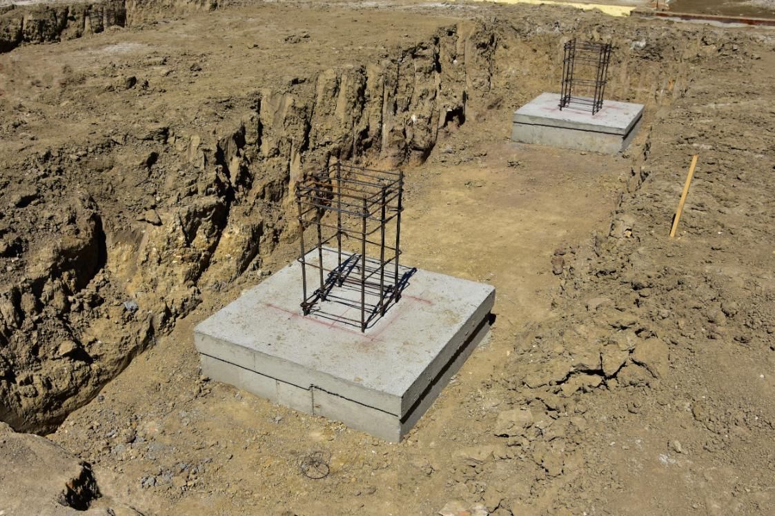 Concrete foundations with steel reinforcement in a construction site excavation.