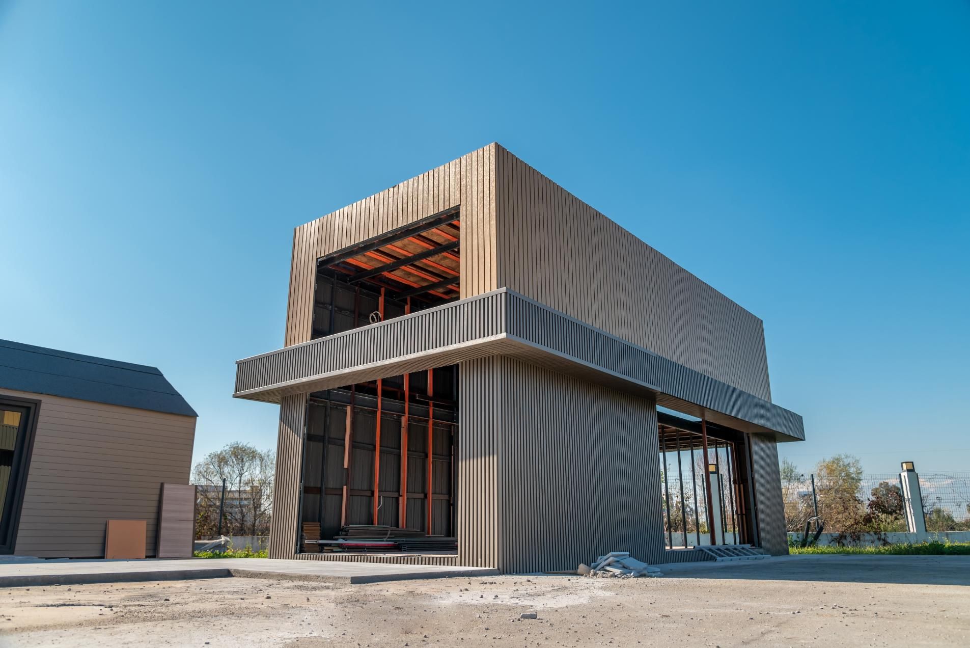 Building with wavy, textured panels; open frame interior; blue sky.