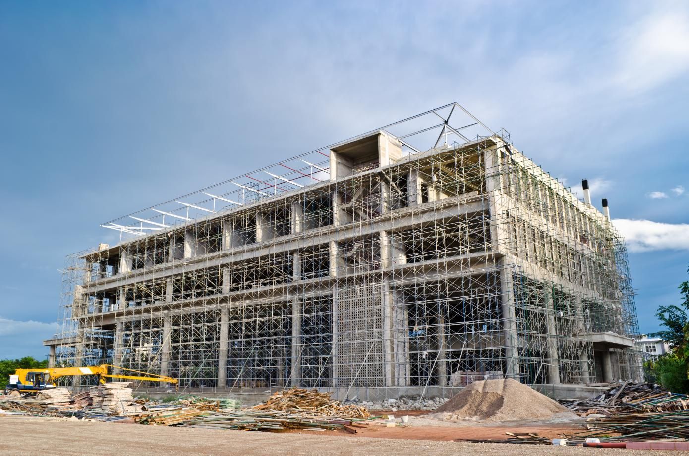 Building under construction with scaffolding against a cloudy sky.