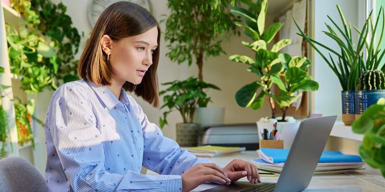 A woman is sitting at a desk using a laptop computer.