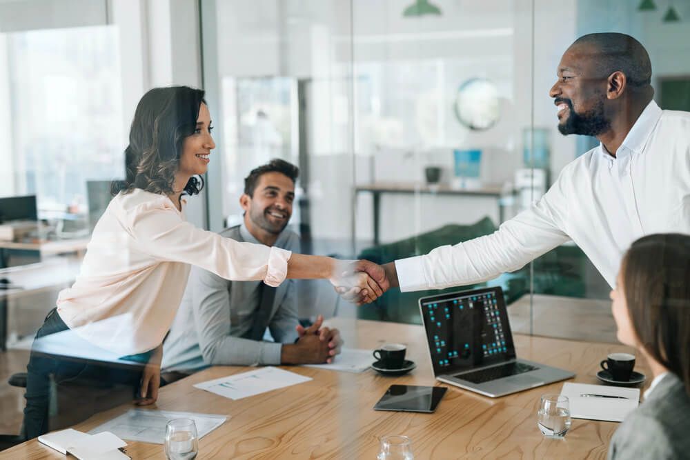 A man and a woman are shaking hands in a conference room.