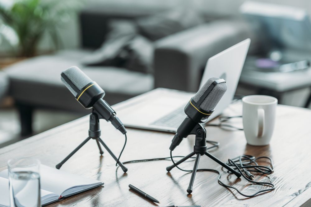 A set of microphones and a laptop on a desk, the equipment you need for a podcast.