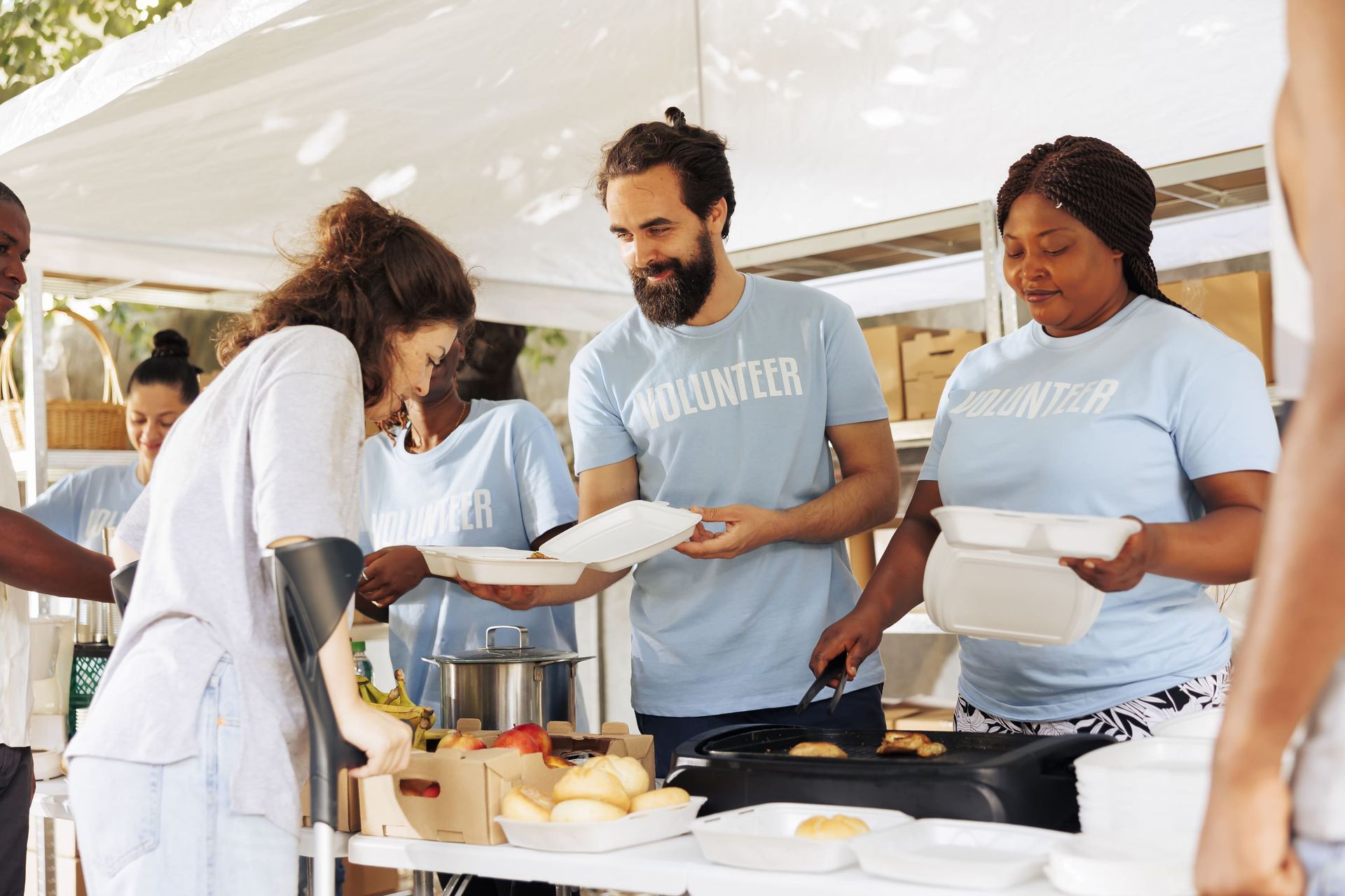 Volunteers serving food to person on crutches.