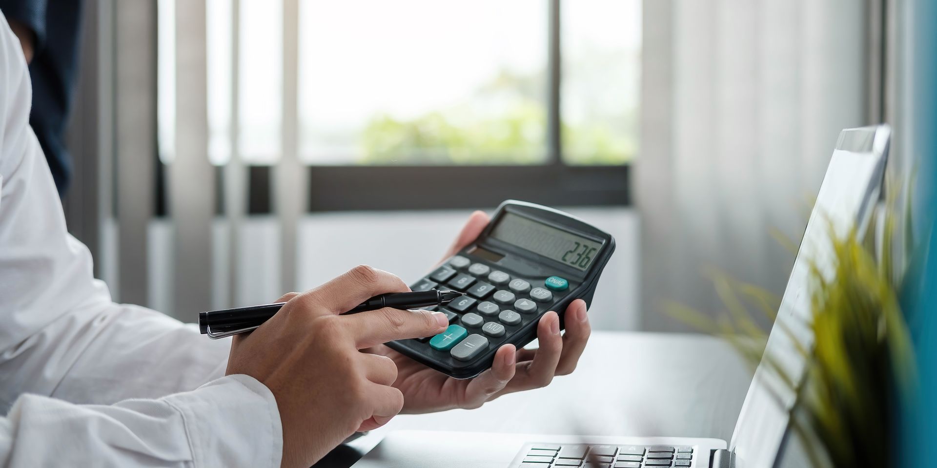 Close up Business woman using calculator and laptop for do math finance on wooden desk in office 