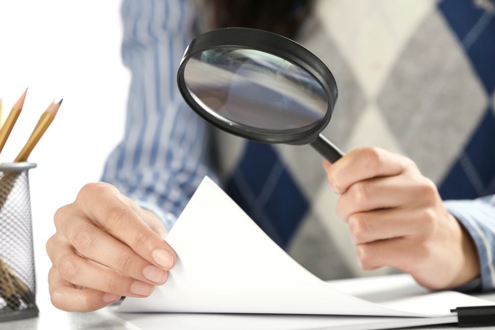A person is holding a magnifying glass over a piece of paper
