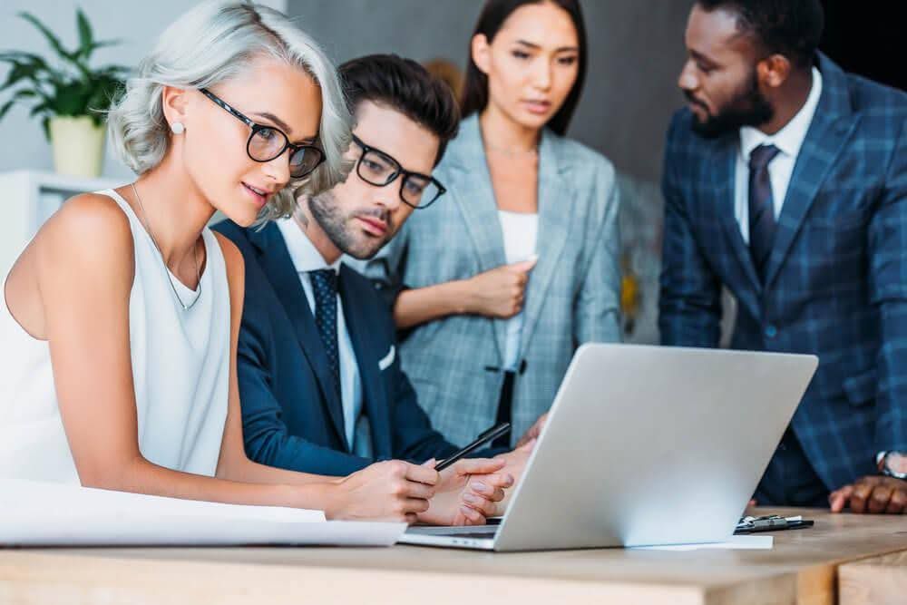 A group of business people are looking at a laptop computer.