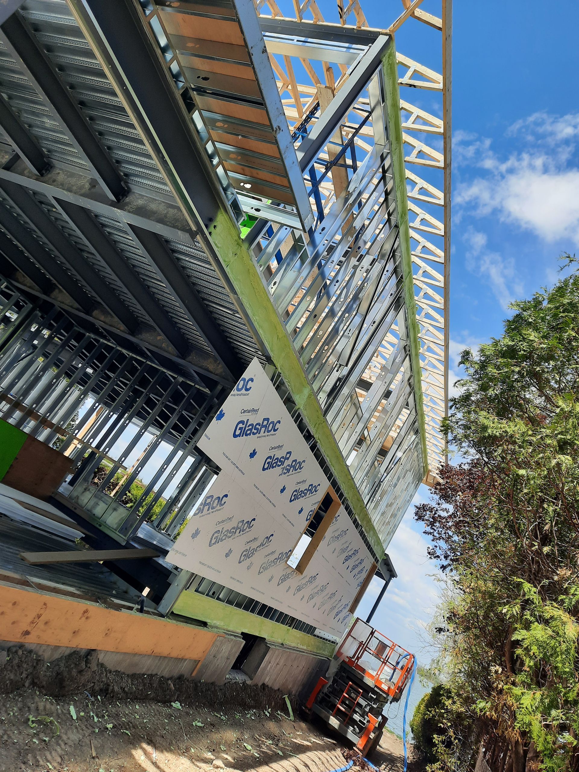 Chantier : bâtiment à ossature métallique avec isolation, échafaudage et ouvriers.