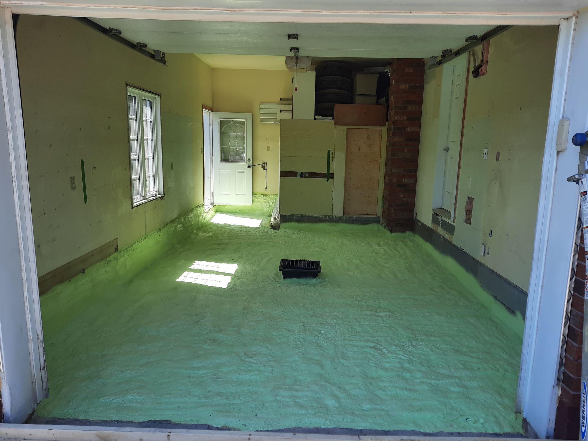 Pièce intérieure avec isolation vert clair recouvrant le sol, porte ouverte à l'avant.