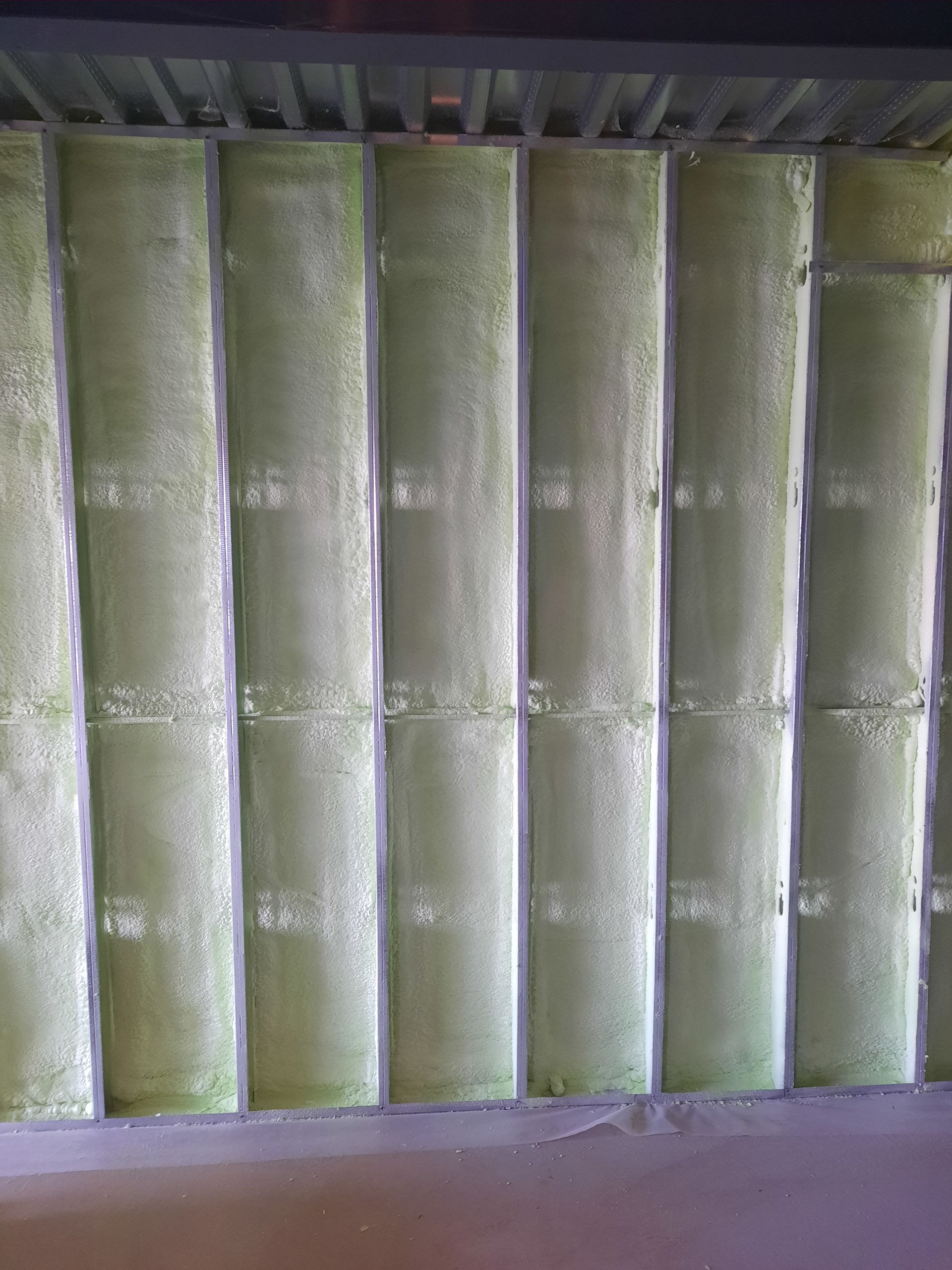 Panneaux verticaux verts avec garniture foncée, éventuellement isolant, sous un plafond sombre.