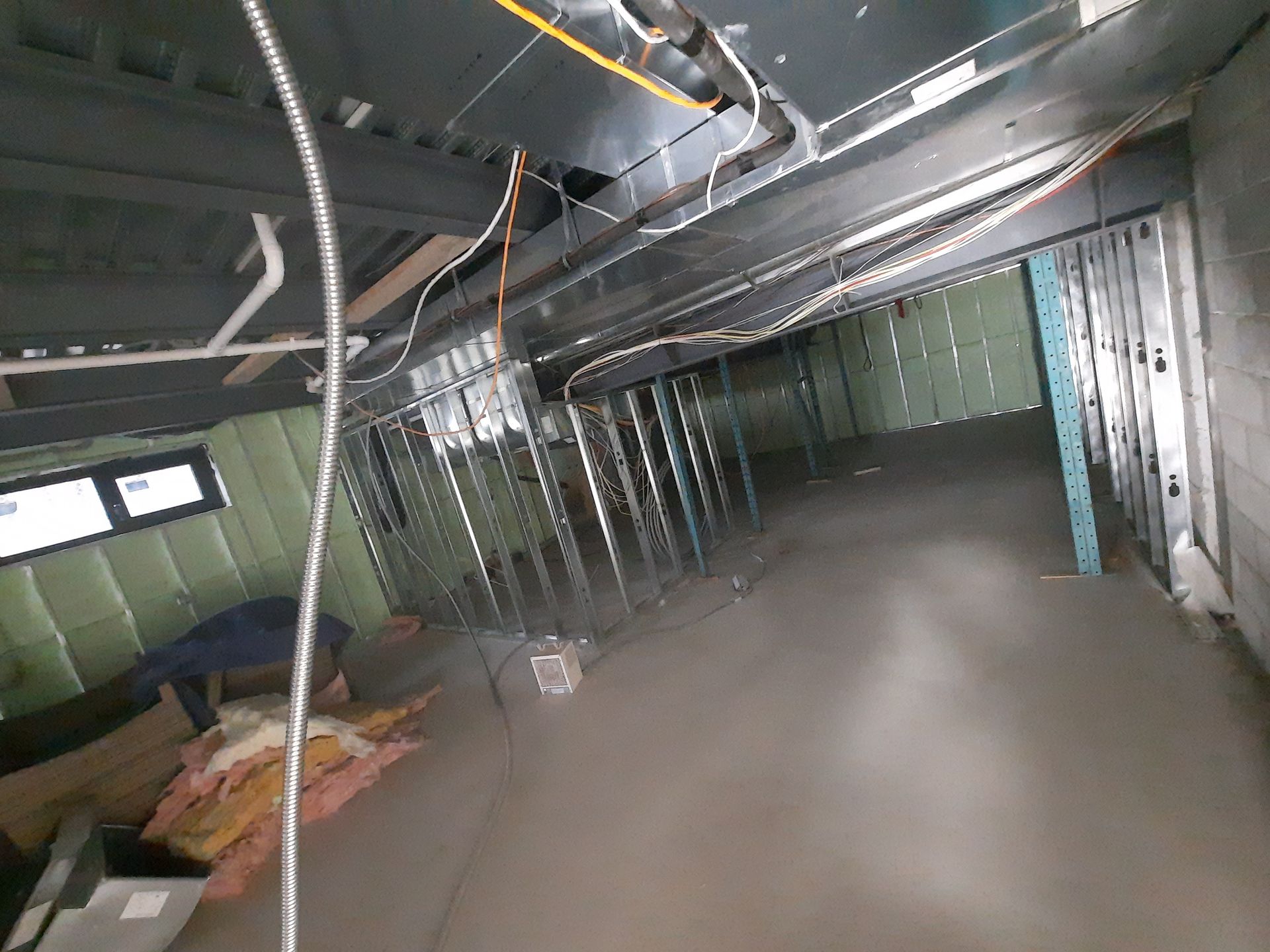 Sous-sol en construction avec ossature métallique, câblage et plancher en béton. Isolation écologique des murs.