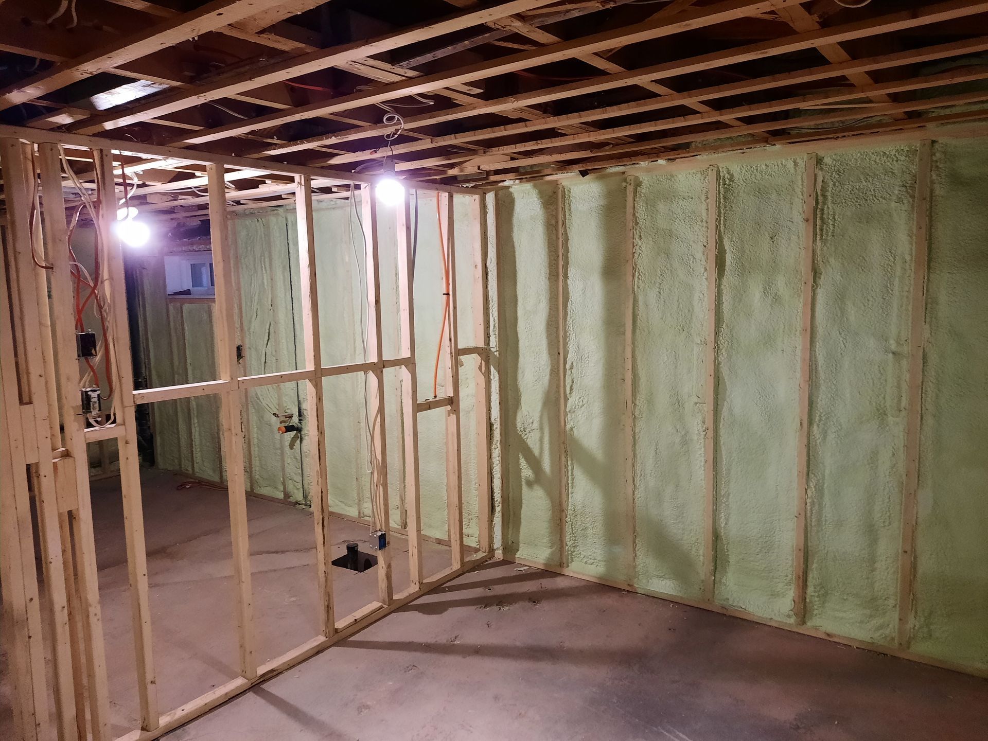 Intérieur d'un sous-sol avec ossature de bois et murs recouverts d'isolant vert.