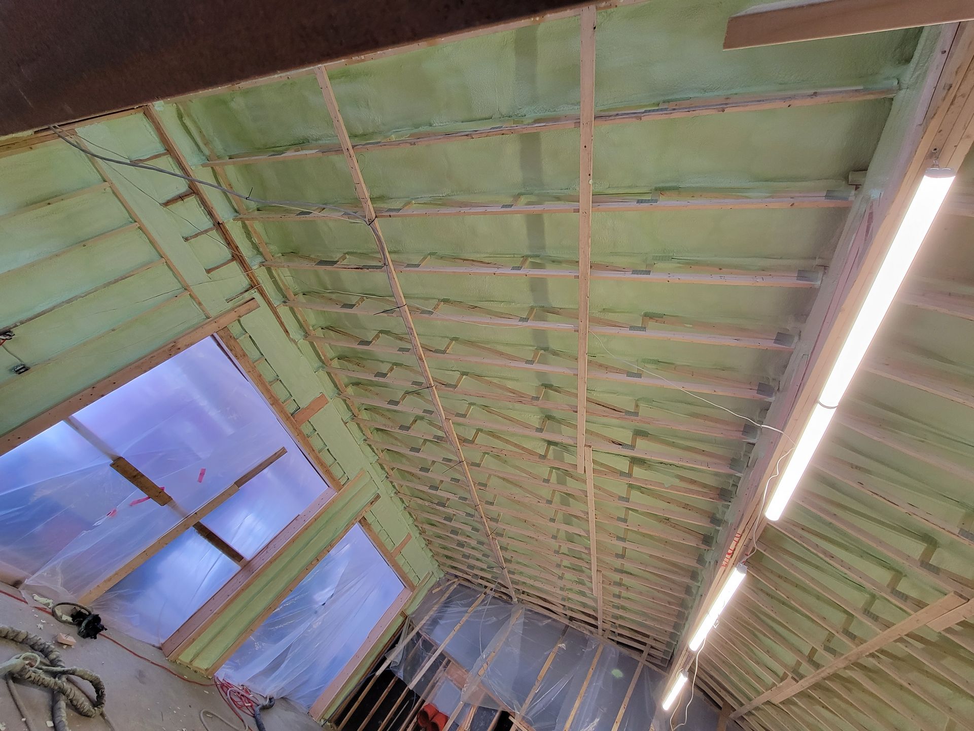 Vue intérieure d'un bâtiment avec ossature bois apparente et isolation végétale, incluant une fenêtre avec revêtement translucide.