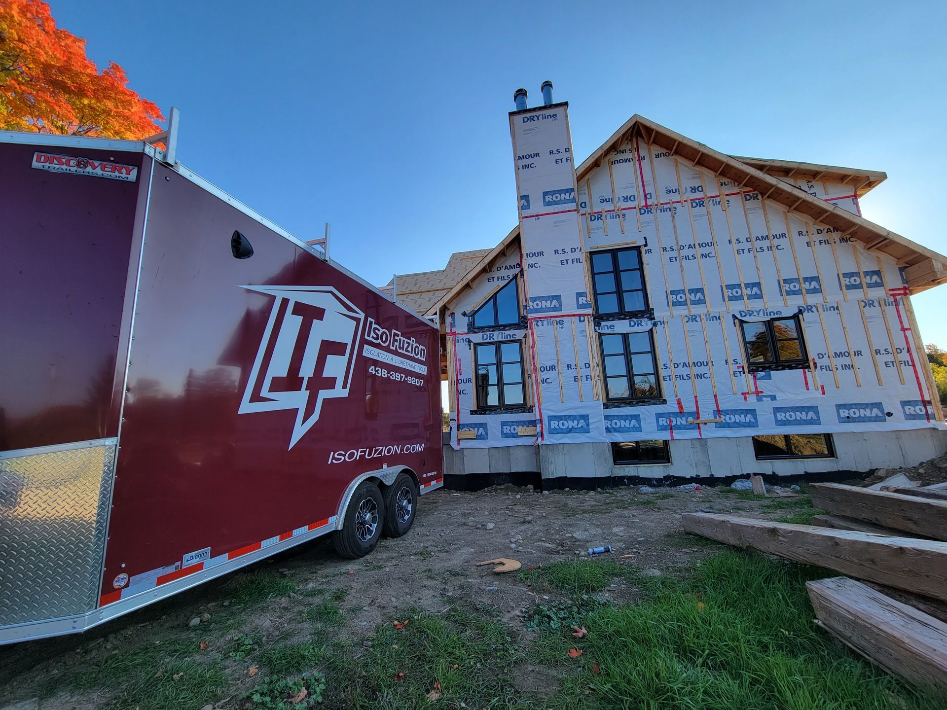 Remorque rouge garée près d'une maison partiellement construite avec une pellicule bleue.