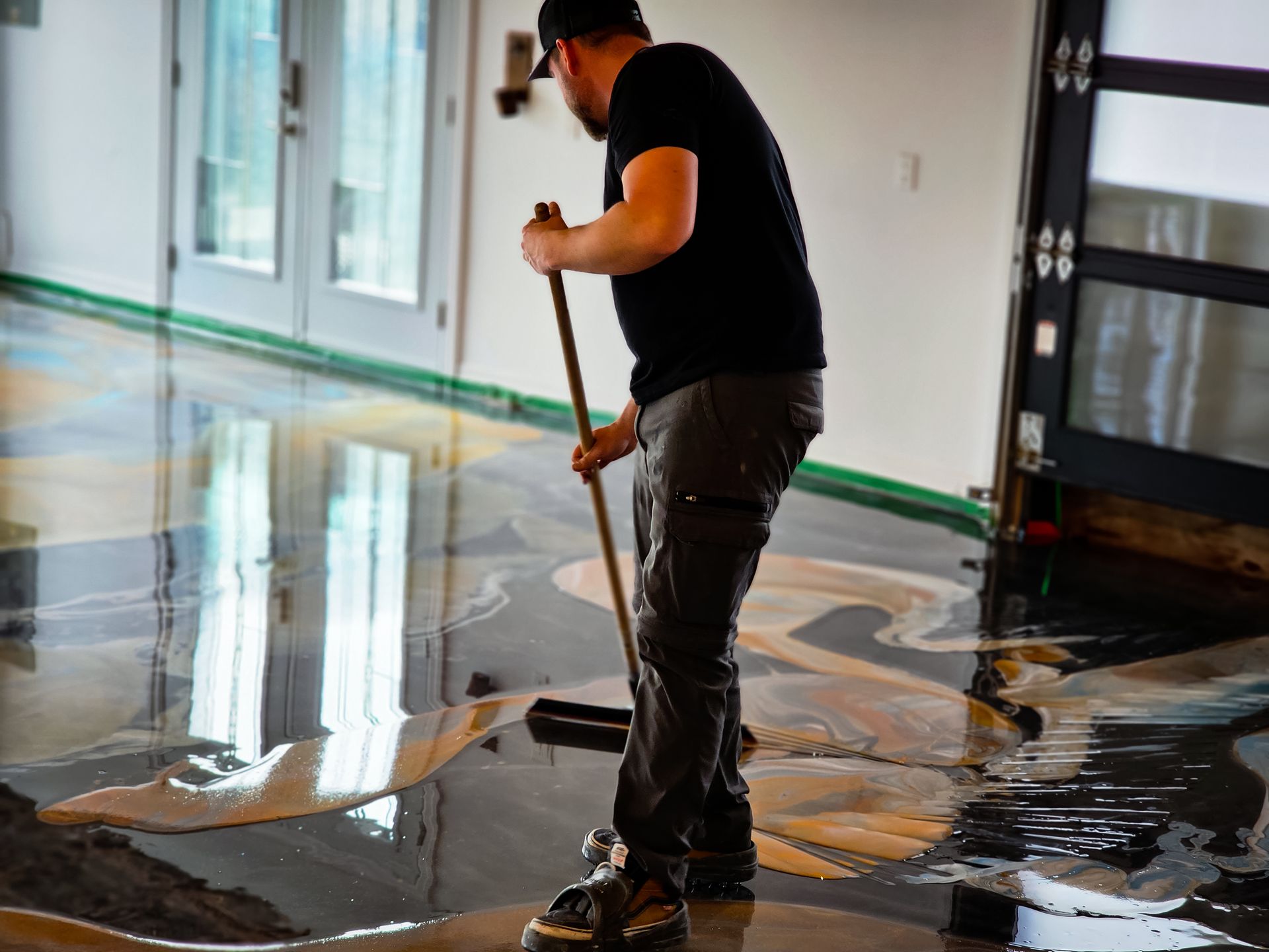 Man applying epoxy to a floor, creating a decorative metallic finish.