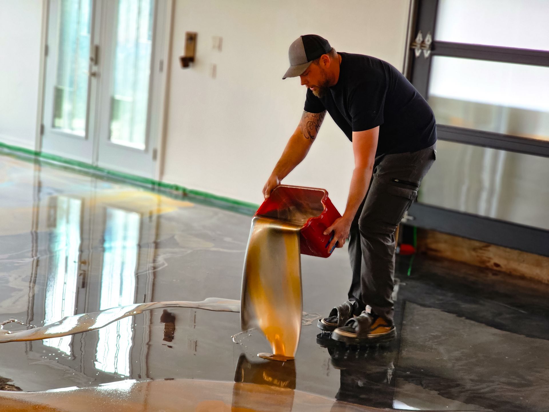 Man pouring epoxy onto a polished concrete floor. White and tan colors.