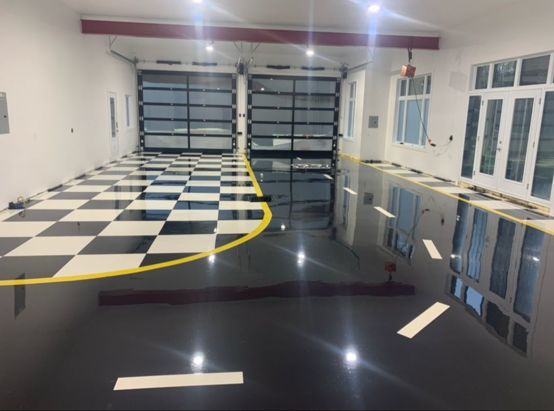 Garage with checkered black and white floor leading to black epoxy floor, two glass garage doors.