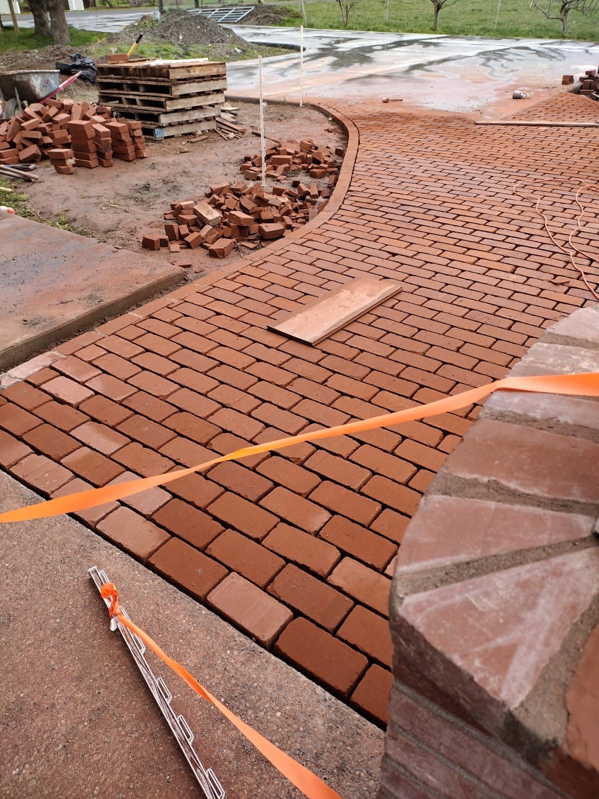 Brick walkway under construction with orange safety tape.