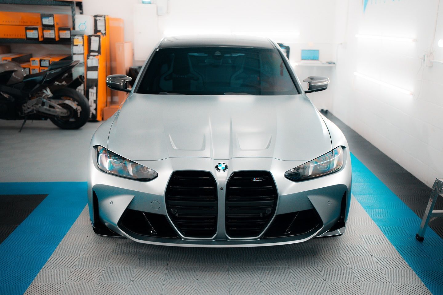 Green Porsche sports car with black hood in a garage.
