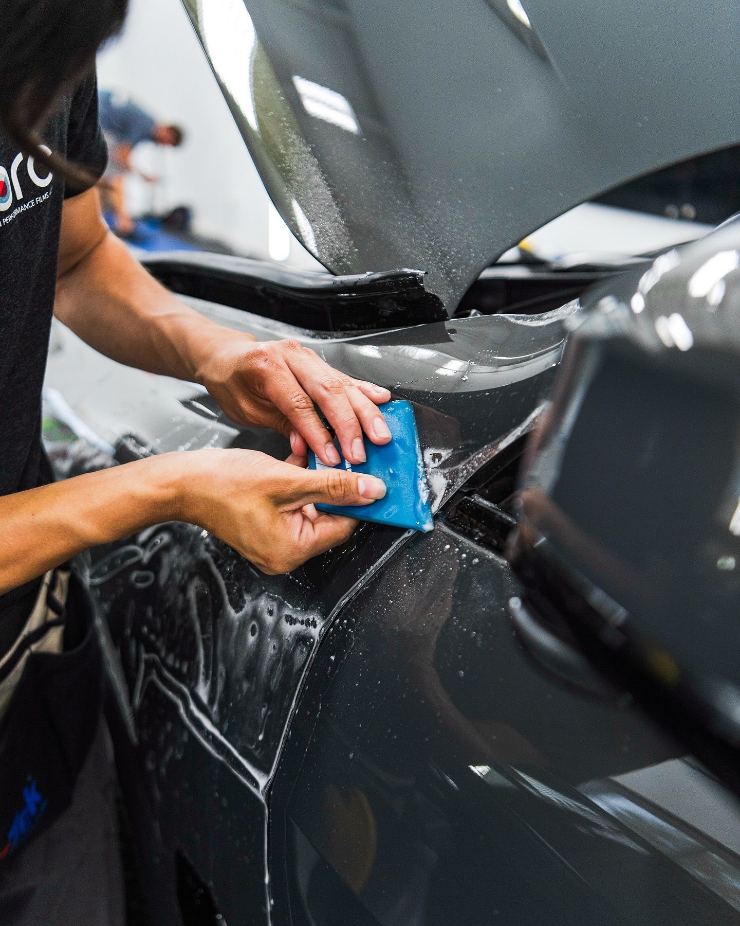 A technician applying Paint Protection Film (PPF) to a vehicle.