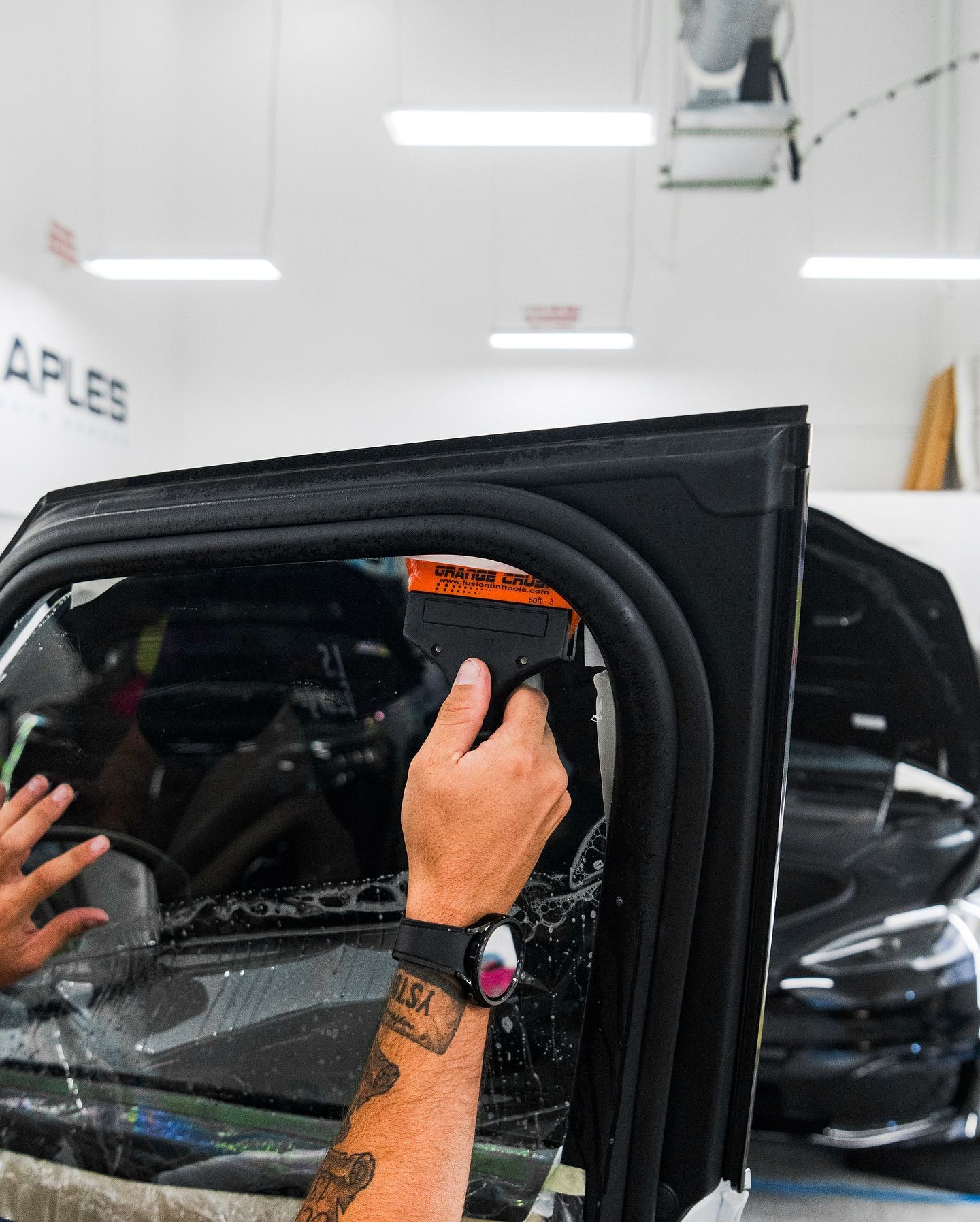A technician installing window tinting on a car door.