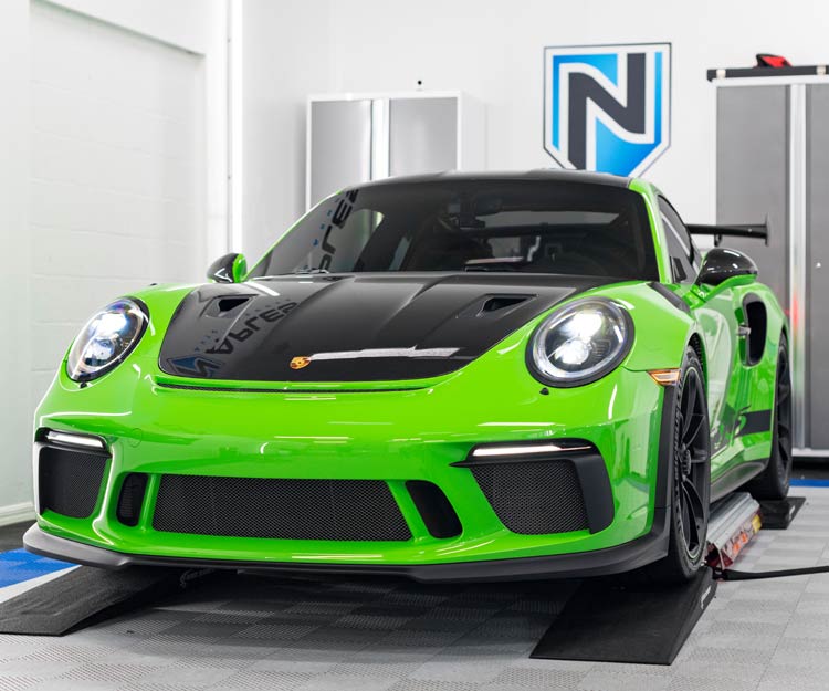 a green porsche 911 gt3 rs is parked in a garage .
