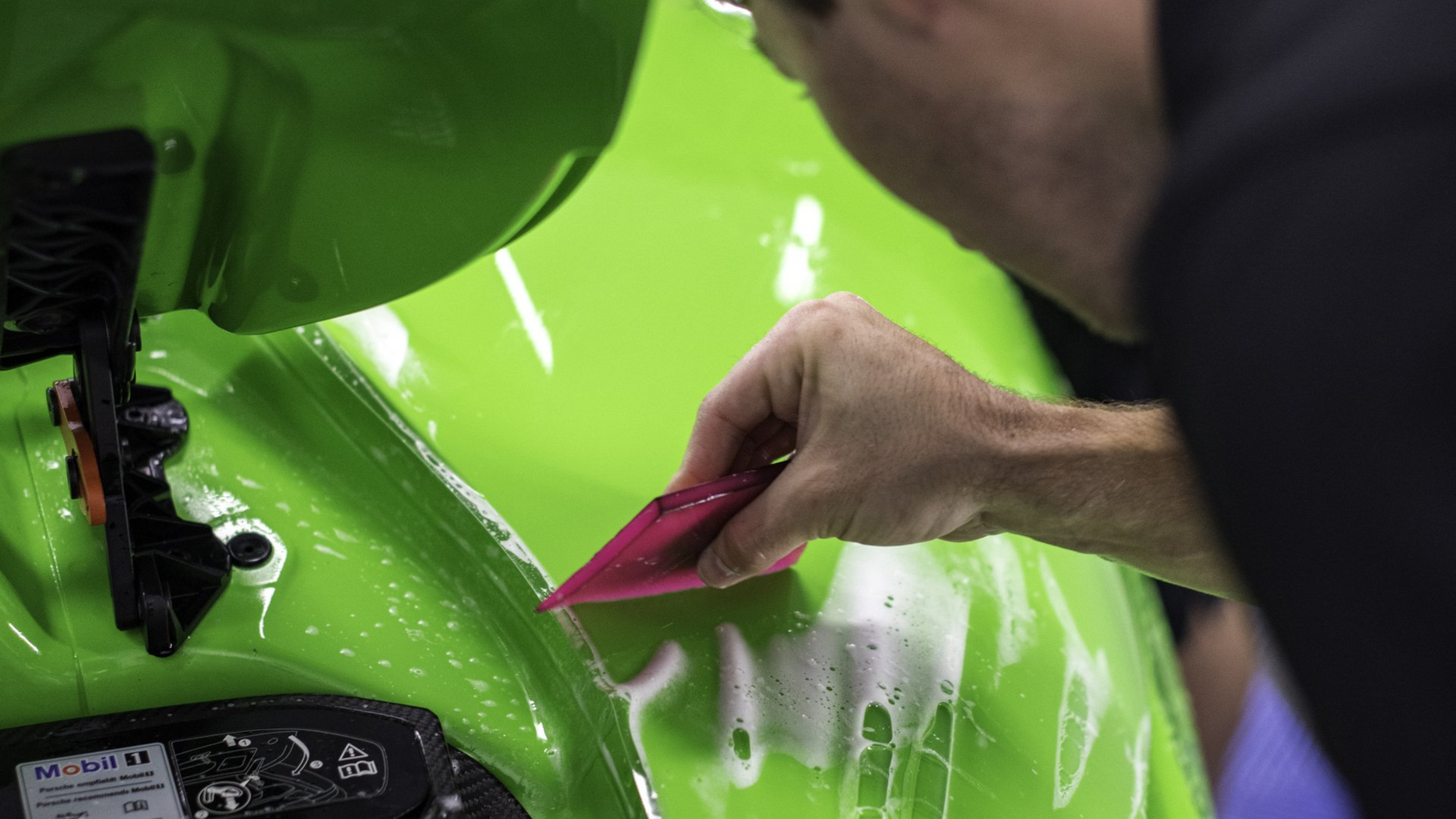 a professional applying ppf on a green car