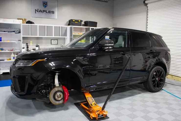 A black range rover is sitting on a jack in a garage.