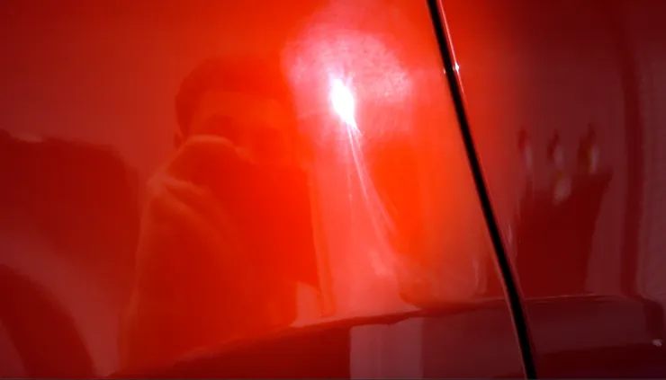 A person is taking a picture of a red car