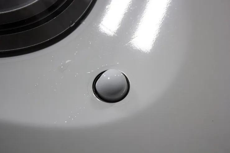 A close up of a white stove top with a black button on it.