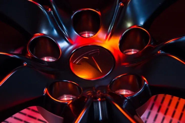 A close up of a tesla wheel with a logo on it