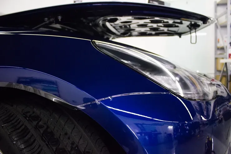 A close up of a blue car with the hood open