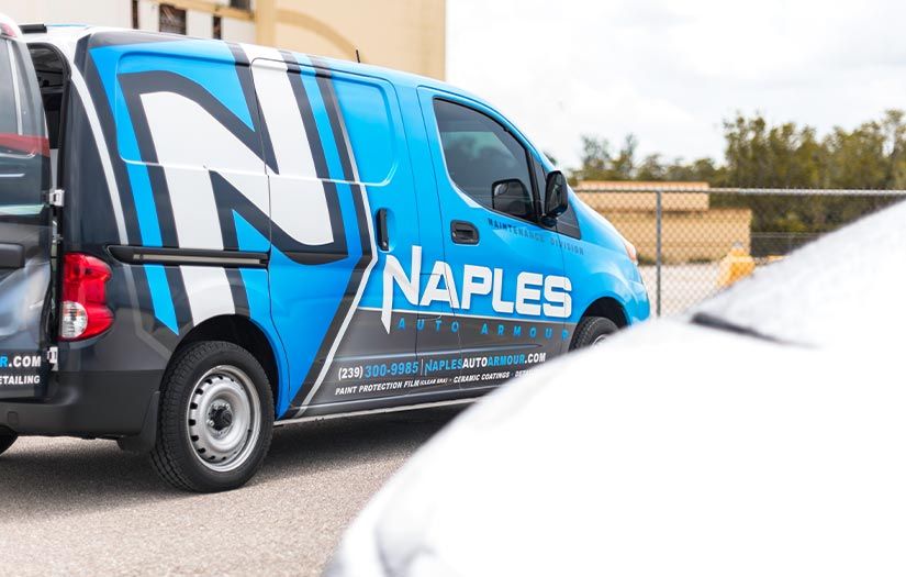 A blue and white van with the word naples on the side is parked in a parking lot.