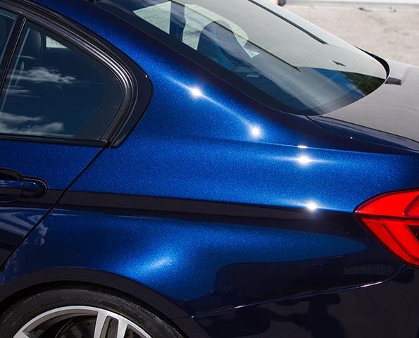 A close up of a blue car with a red tail light