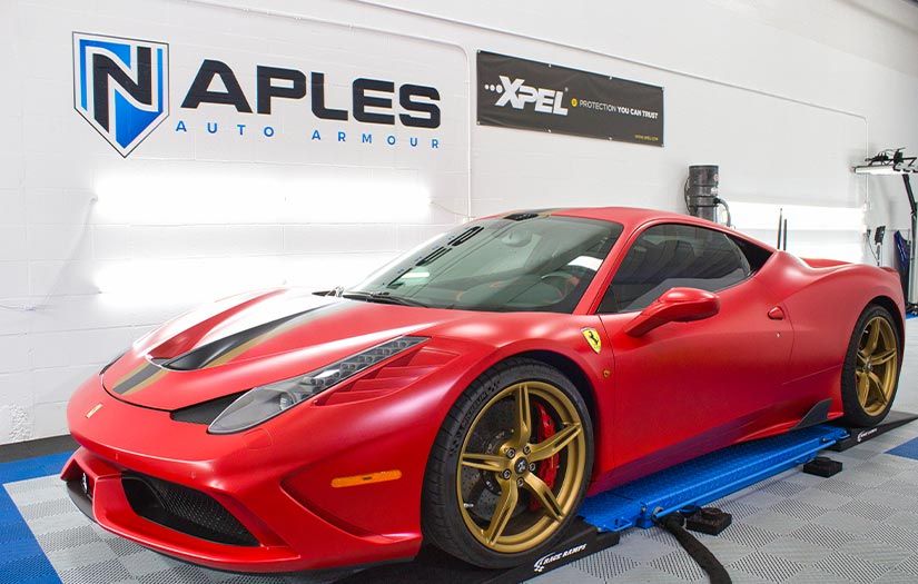 A red ferrari is parked on a ramp in a garage.