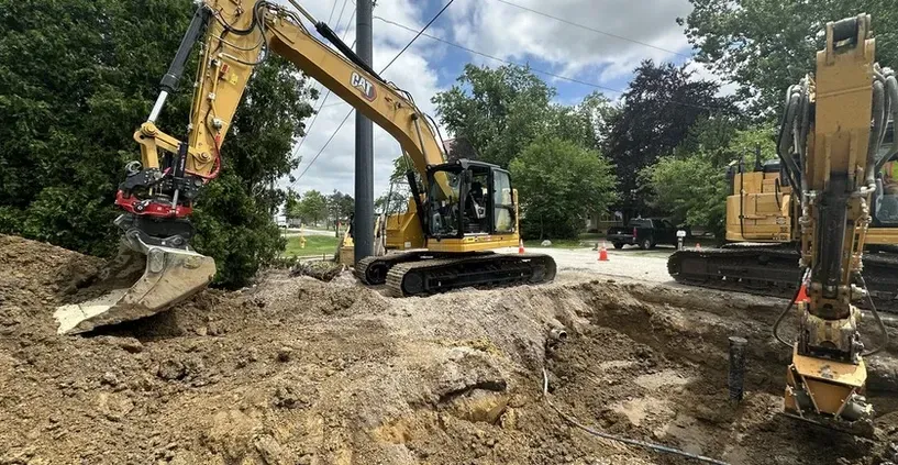 A couple of excavators are digging a hole in the ground.