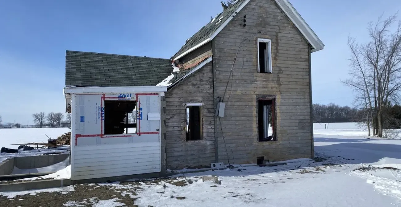 A small house is sitting in the middle of a snowy field.