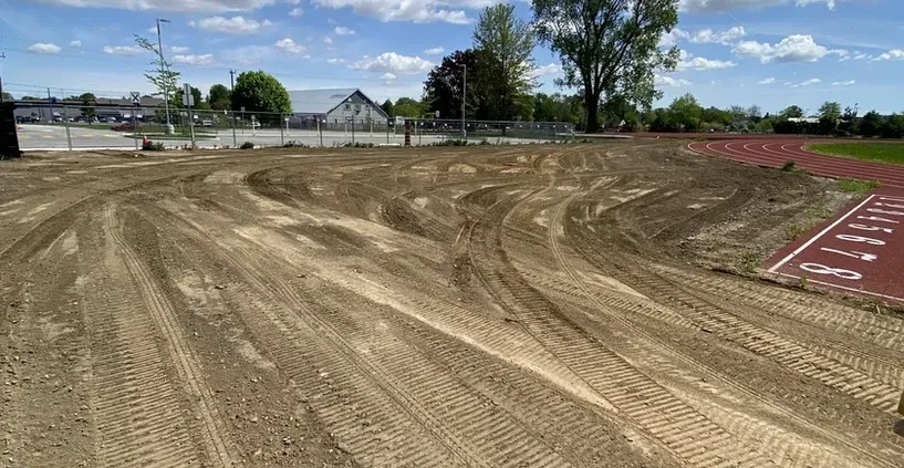 A dirt track with a red track in the background.