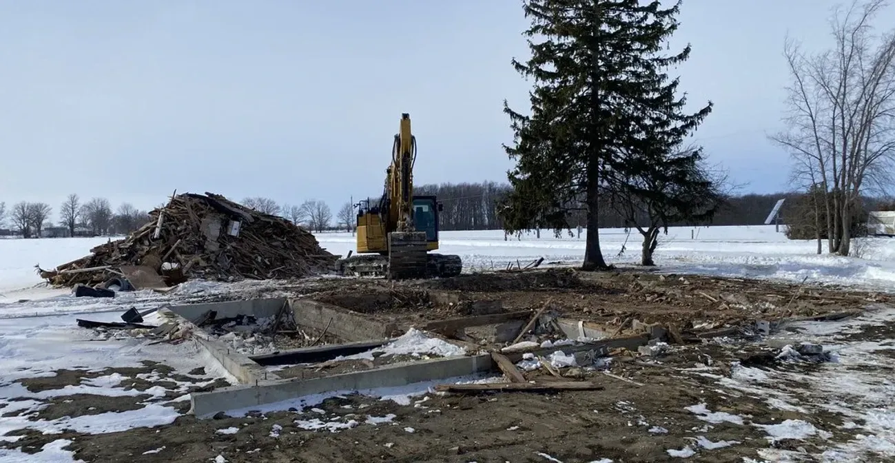 A large excavator is sitting in the middle of a snowy field.