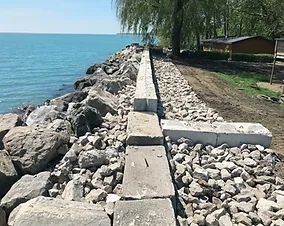 A concrete wall is being built on the shore of a lake.