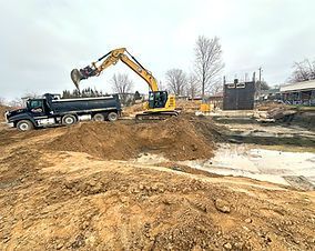 A dump truck is being loaded with dirt by an excavator.