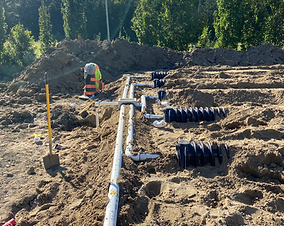 A construction site with a lot of pipes in the dirt.