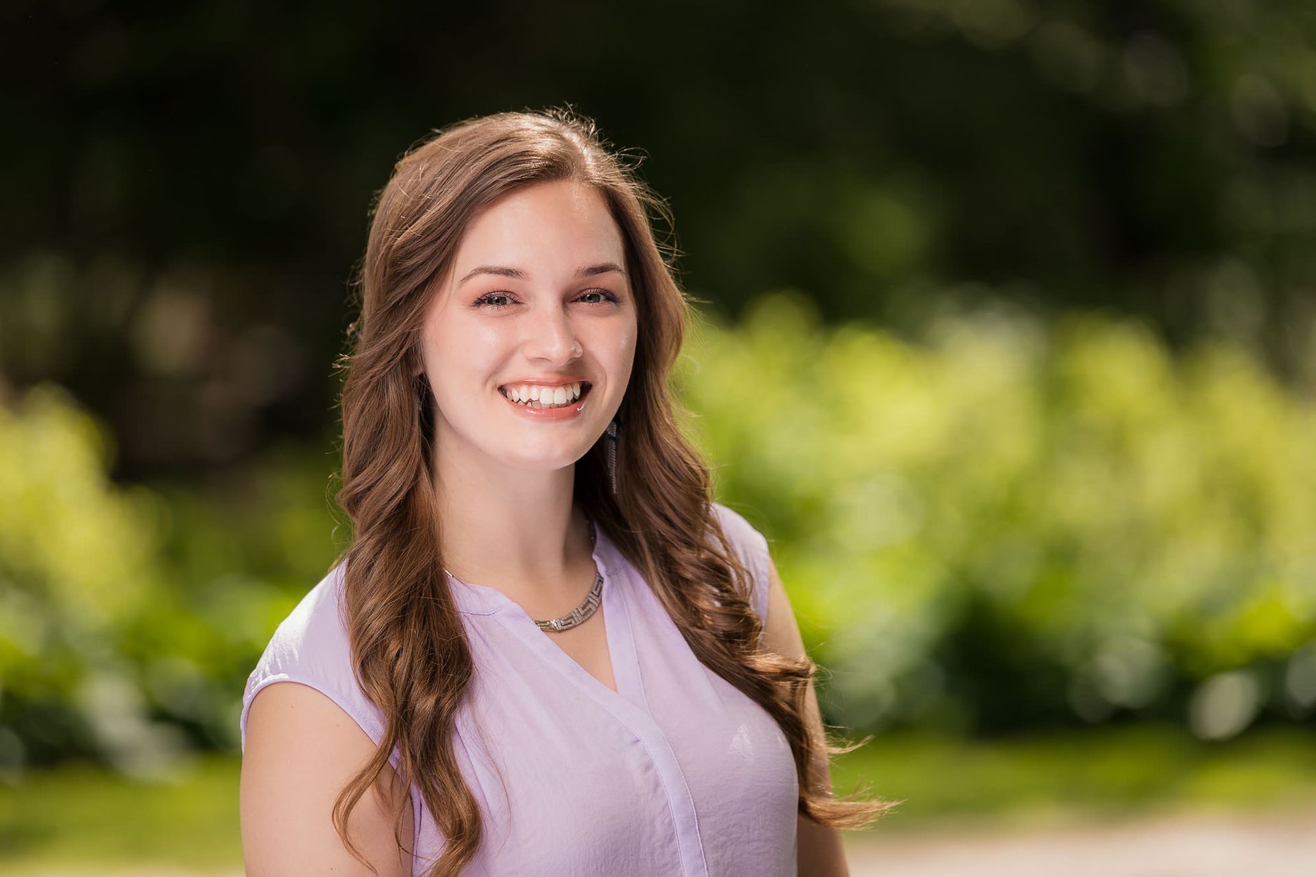 A woman in a purple shirt is smiling for the camera.