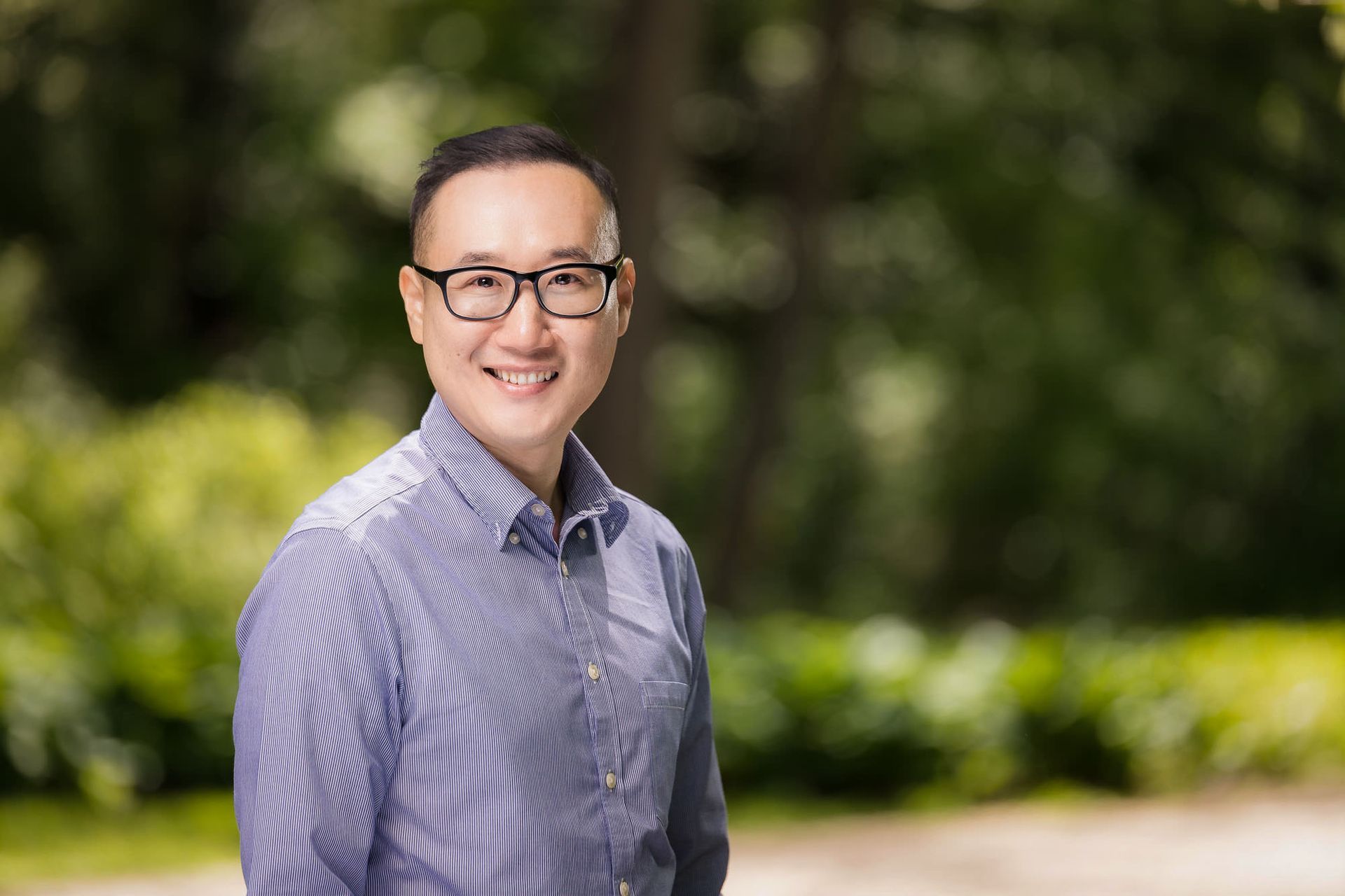 A man wearing glasses and a blue striped shirt is smiling for the camera.