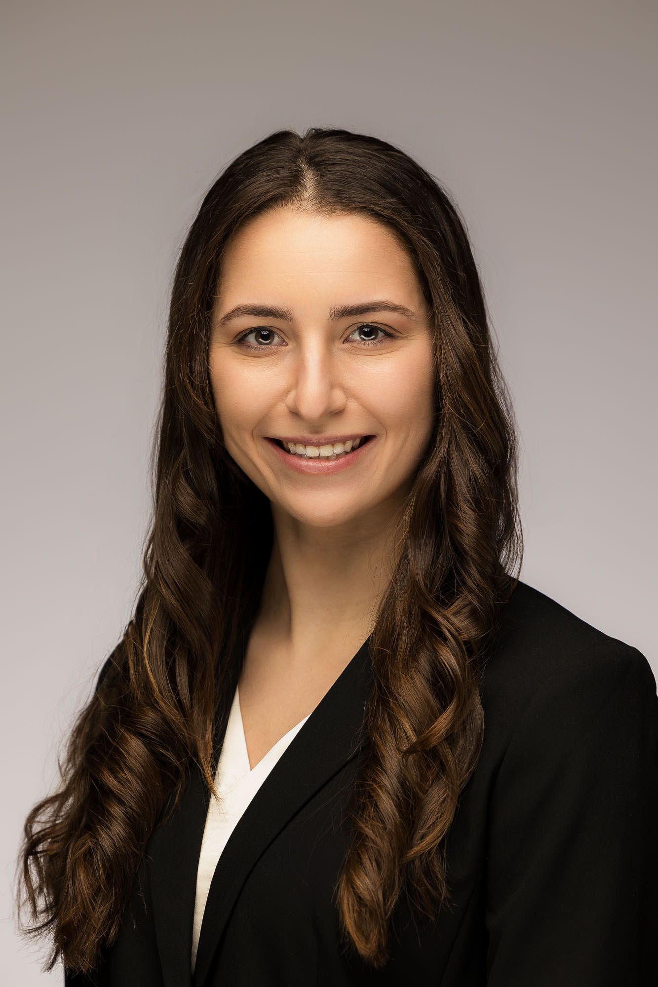 A woman in a black jacket and white shirt is smiling for the camera.