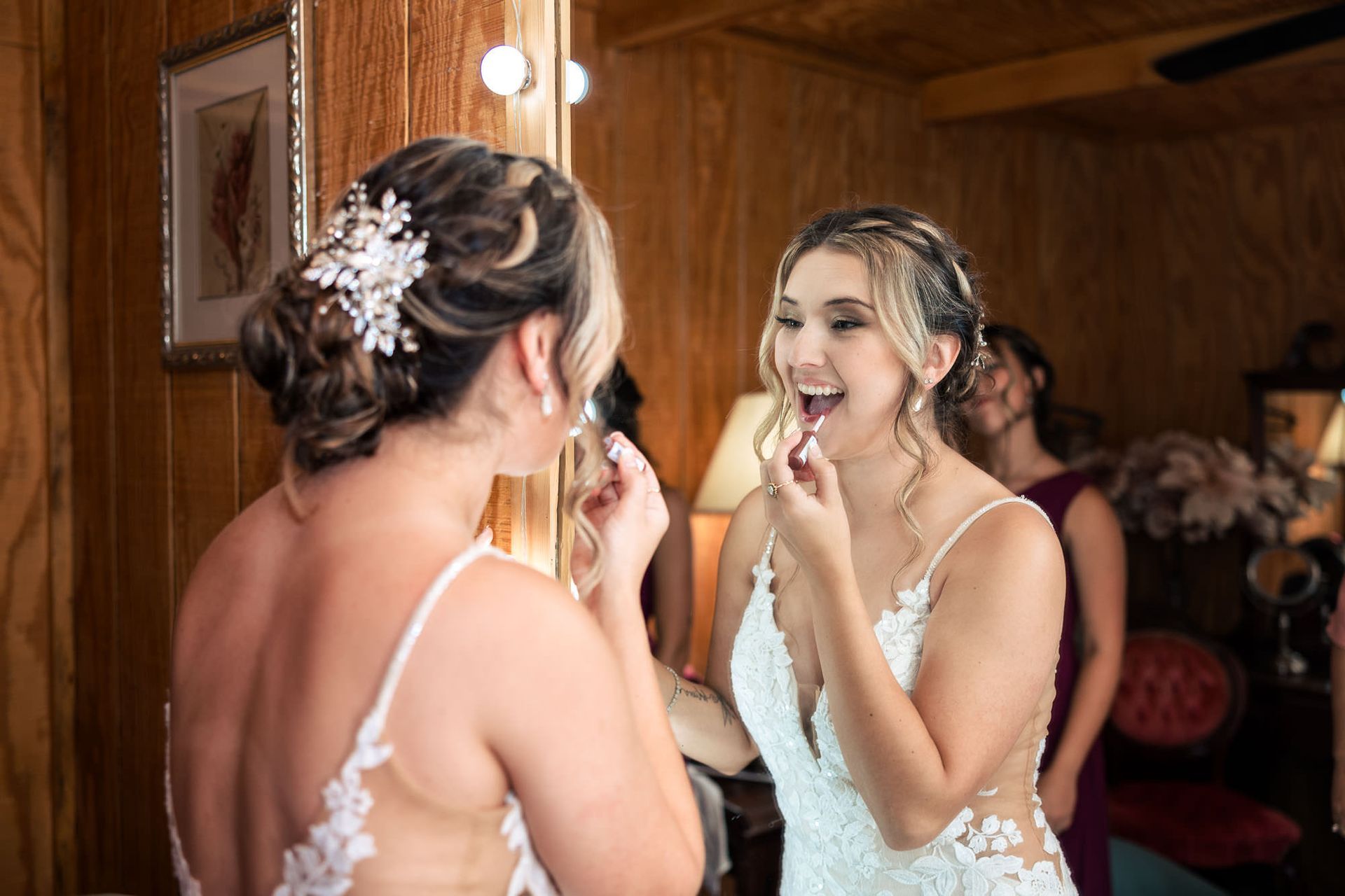 A bride is applying lipstick in front of a mirror.