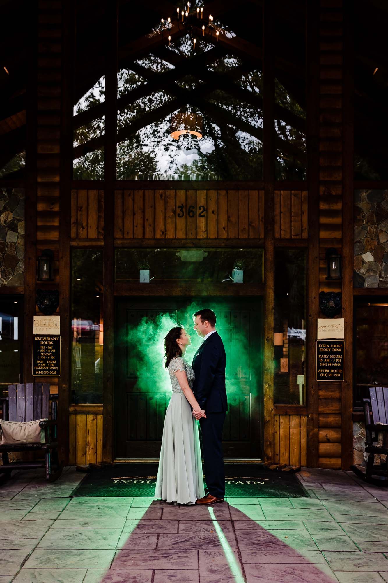 A bride and groom are standing in front of a building with a green light behind them.