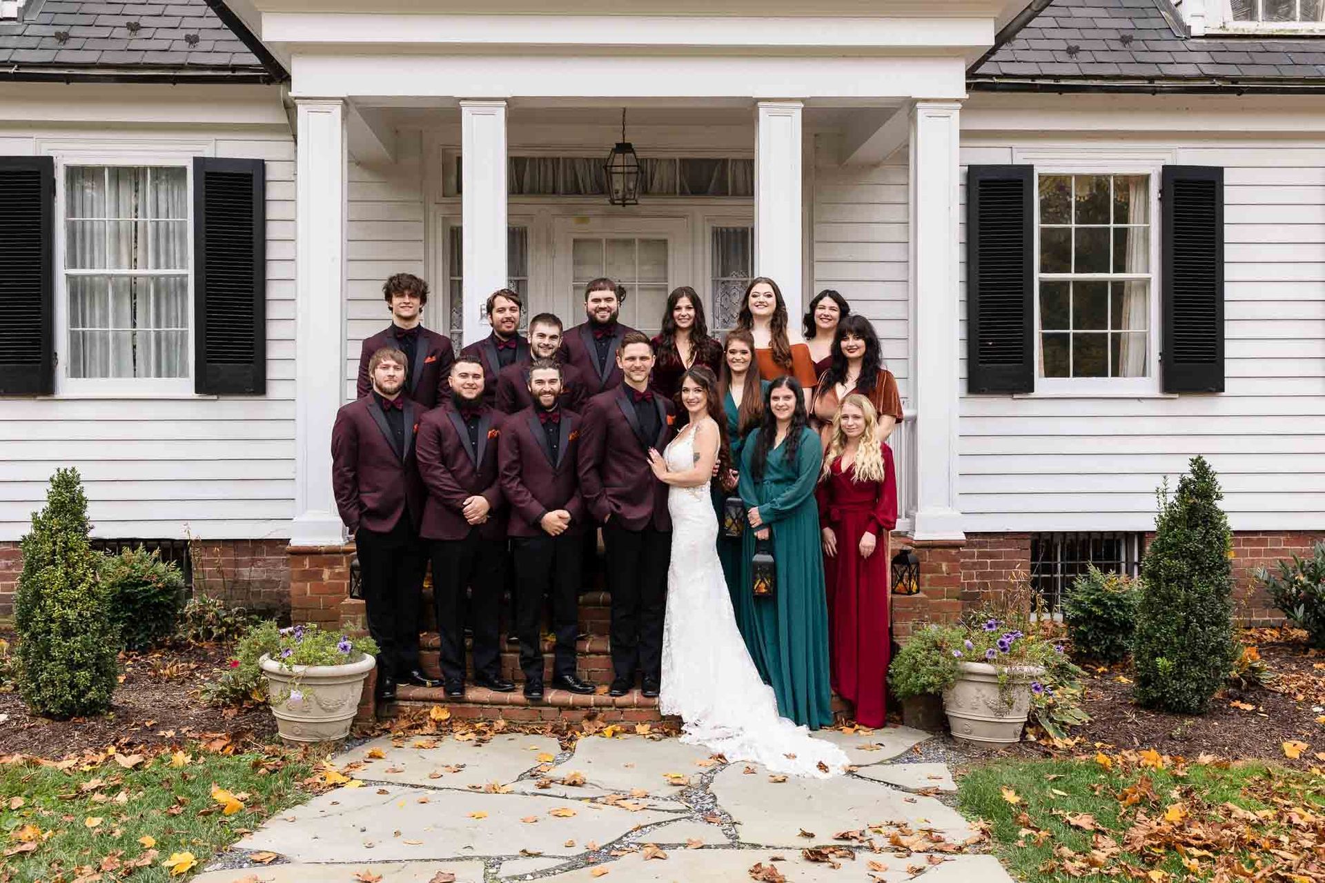 A bride and her wedding party are posing for a picture in front of a white house.