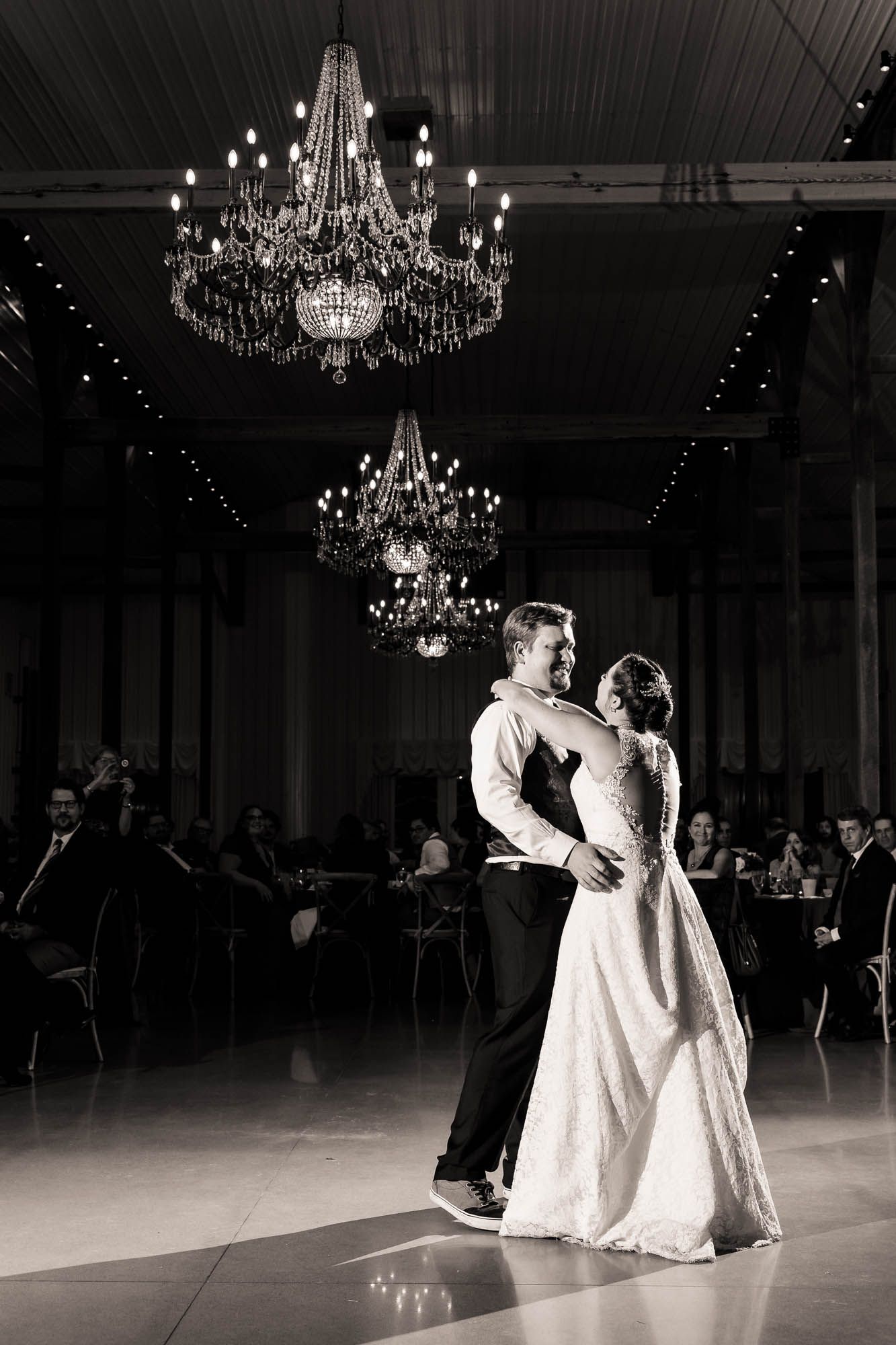A black and white photo of a bride and groom dancing at their wedding reception.