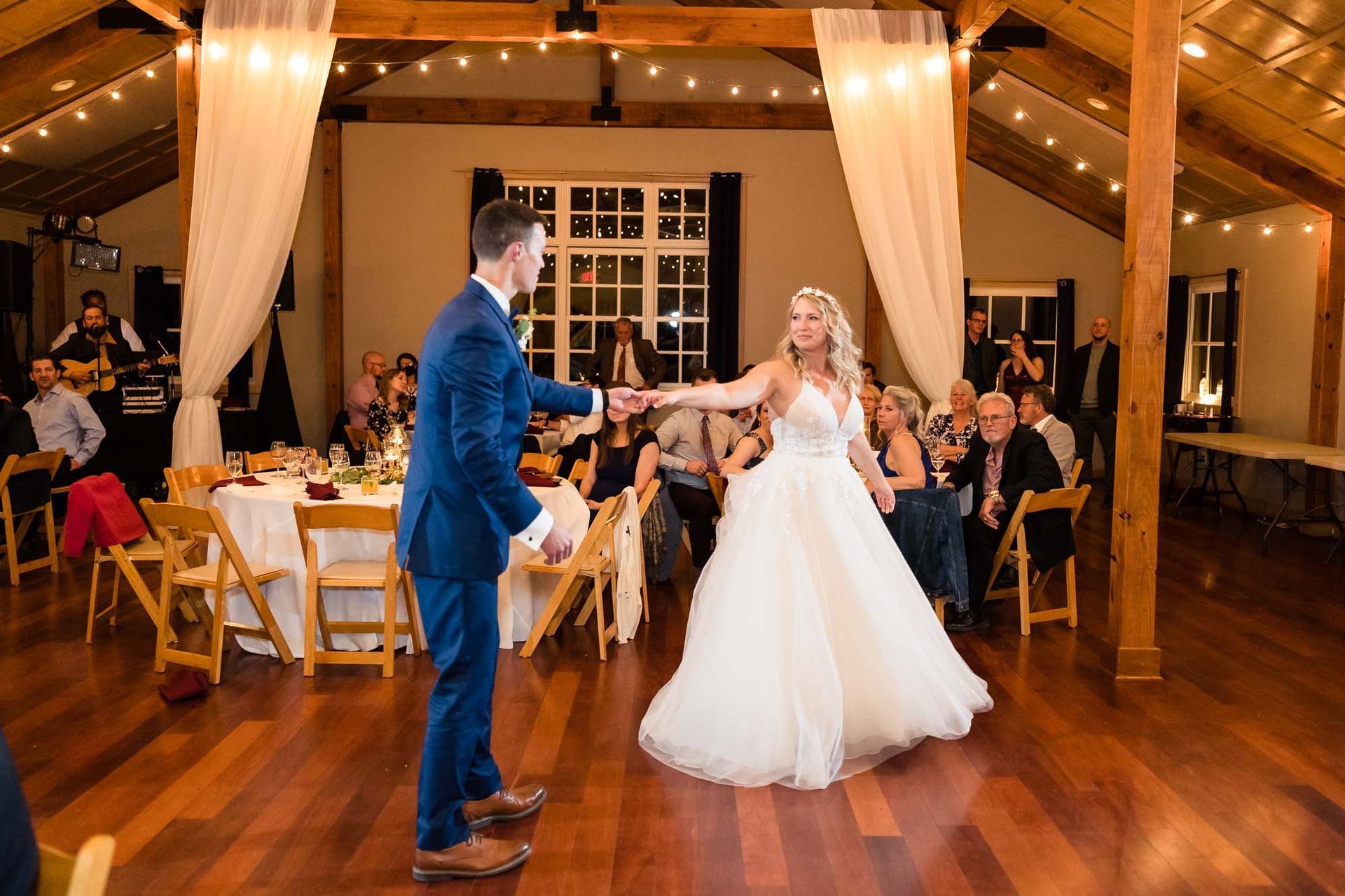 A bride and groom are dancing at their wedding reception in front of their guests.